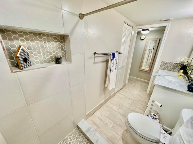 bathroom featuring hardwood / wood-style floors, vanity, toilet, and tasteful backsplash