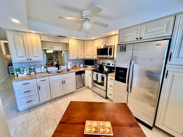 kitchen featuring sink, tasteful backsplash, light stone counters, light hardwood / wood-style flooring, and appliances with stainless steel finishes