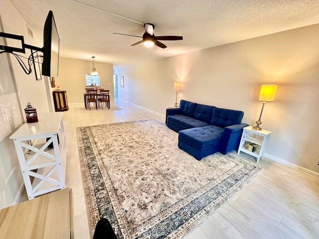 living room featuring ceiling fan, wood-type flooring, and a textured ceiling