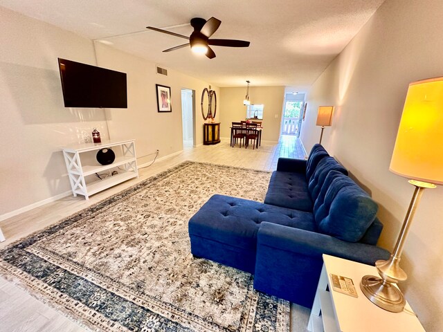 living room with ceiling fan, a textured ceiling, and hardwood / wood-style flooring