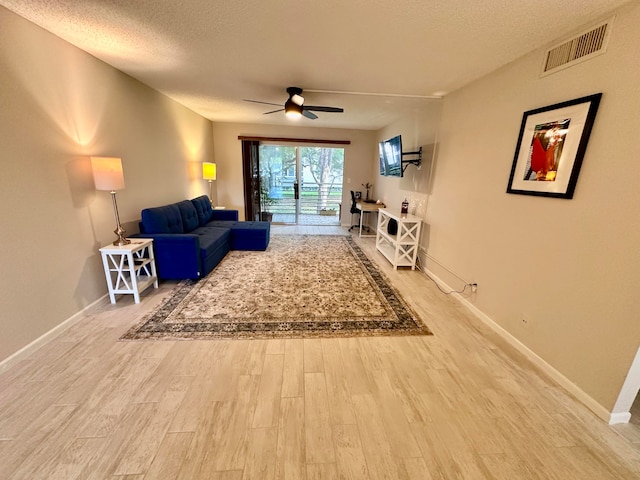 living room featuring wood-type flooring, a textured ceiling, and ceiling fan