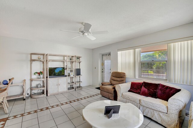 living room with ceiling fan, light tile patterned floors, and a textured ceiling