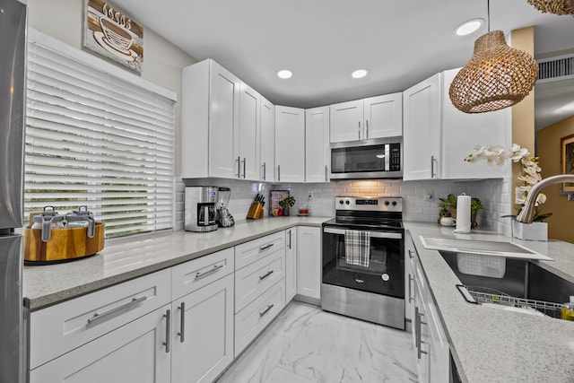 kitchen with light stone countertops, appliances with stainless steel finishes, decorative light fixtures, and white cabinetry