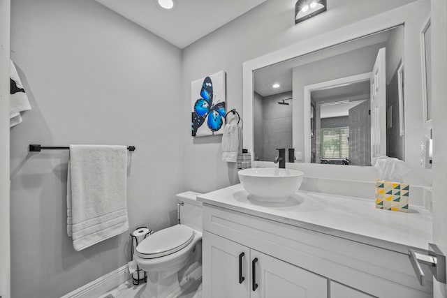 bathroom with a tile shower, vanity, and toilet