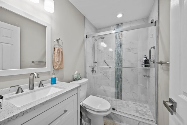 bathroom with a shower with door, vanity, and toilet