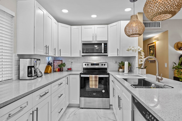 kitchen with white cabinets, sink, light stone countertops, appliances with stainless steel finishes, and decorative light fixtures