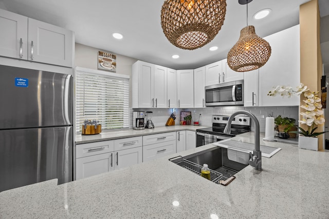 kitchen featuring white cabinetry, light stone counters, decorative light fixtures, and appliances with stainless steel finishes