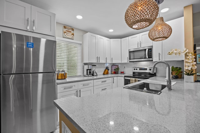 kitchen with white cabinetry, pendant lighting, stainless steel appliances, and light stone counters