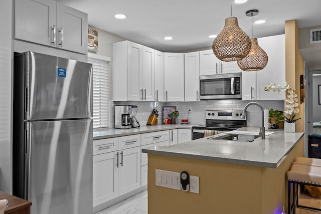 kitchen featuring a breakfast bar, kitchen peninsula, light stone countertops, white cabinetry, and stainless steel appliances