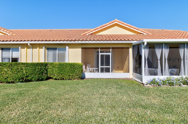 rear view of property with a lawn and a sunroom