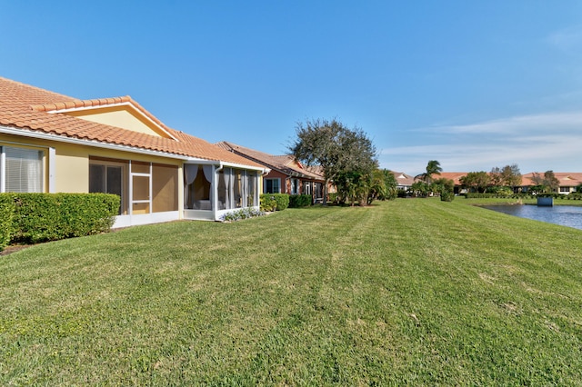 view of yard featuring a sunroom and a water view