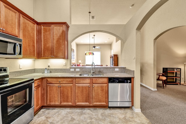 kitchen featuring ceiling fan, sink, stainless steel appliances, light colored carpet, and decorative light fixtures