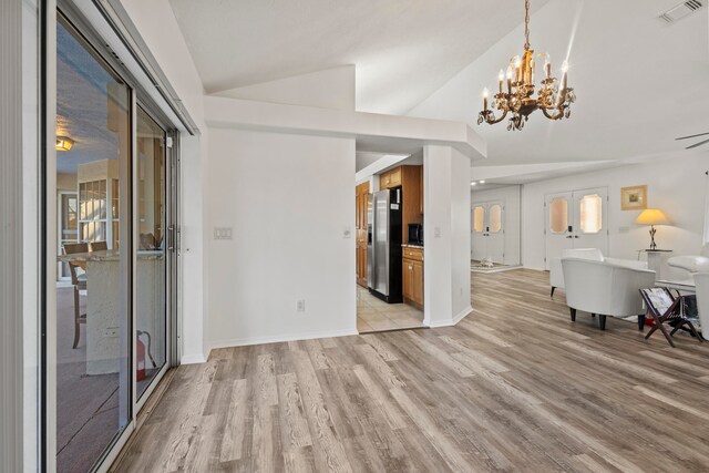 unfurnished dining area featuring a chandelier, a healthy amount of sunlight, lofted ceiling, and light hardwood / wood-style flooring