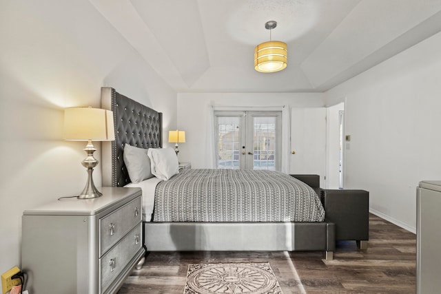 bedroom featuring french doors, dark hardwood / wood-style flooring, access to outside, and a tray ceiling