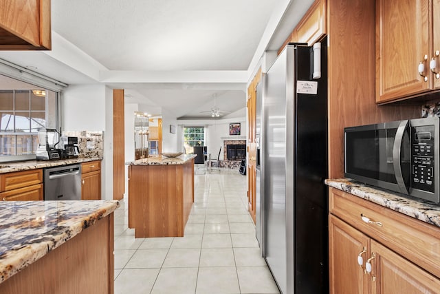 kitchen with lofted ceiling, ceiling fan, light stone countertops, light tile patterned floors, and stainless steel appliances