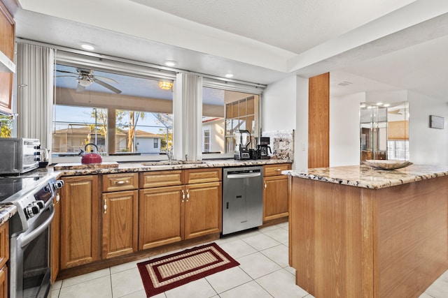 kitchen featuring light stone countertops, appliances with stainless steel finishes, ceiling fan, sink, and light tile patterned flooring