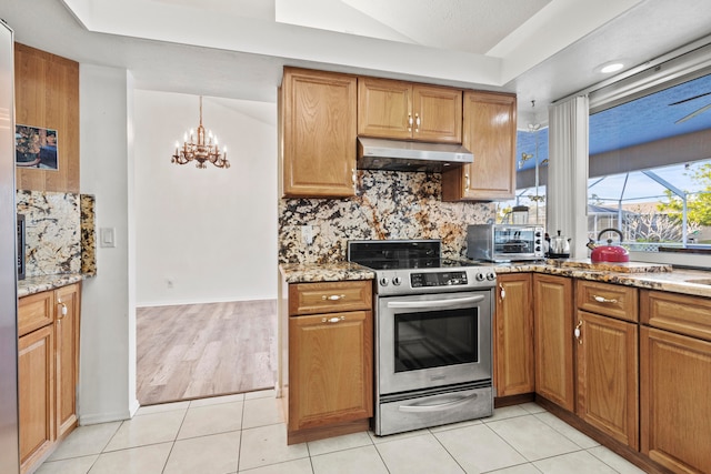 kitchen featuring light tile patterned flooring, light stone counters, stainless steel stove, and a chandelier