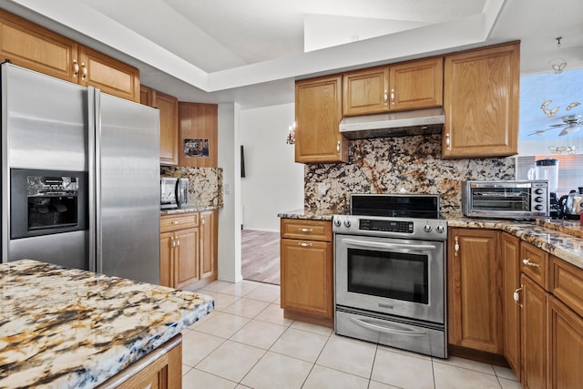 kitchen featuring light tile patterned floors, stainless steel appliances, and light stone counters