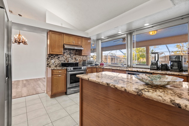 kitchen featuring light stone countertops, appliances with stainless steel finishes, sink, lofted ceiling, and light tile patterned flooring