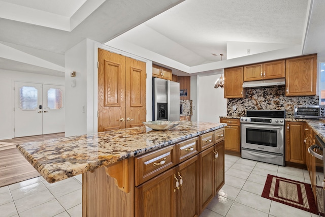 kitchen featuring a center island, stainless steel appliances, tasteful backsplash, lofted ceiling, and light tile patterned flooring