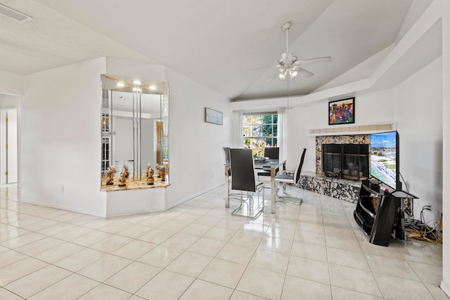 dining space with a premium fireplace, light tile patterned flooring, vaulted ceiling, and ceiling fan