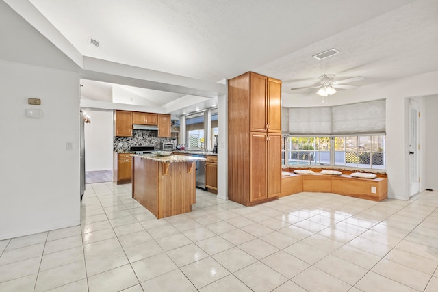 kitchen with dishwasher, a healthy amount of sunlight, a kitchen island, and light tile patterned flooring