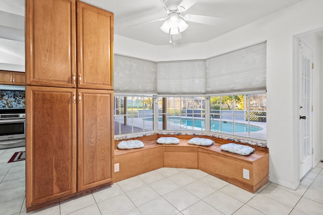 interior space featuring oven, ceiling fan, light stone counters, and light tile patterned floors