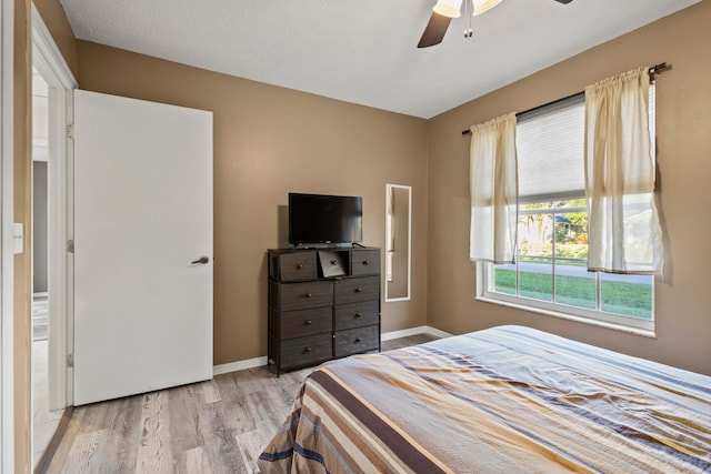 bedroom with ceiling fan, a textured ceiling, and light hardwood / wood-style flooring