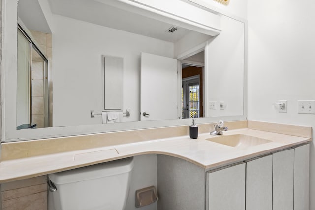 bathroom with vanity, a shower with shower door, and toilet