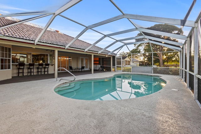 view of pool featuring glass enclosure, an outdoor bar, and a patio