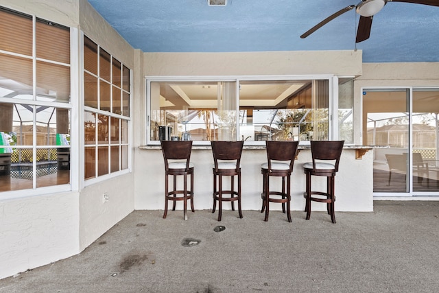 interior space with ceiling fan and exterior bar