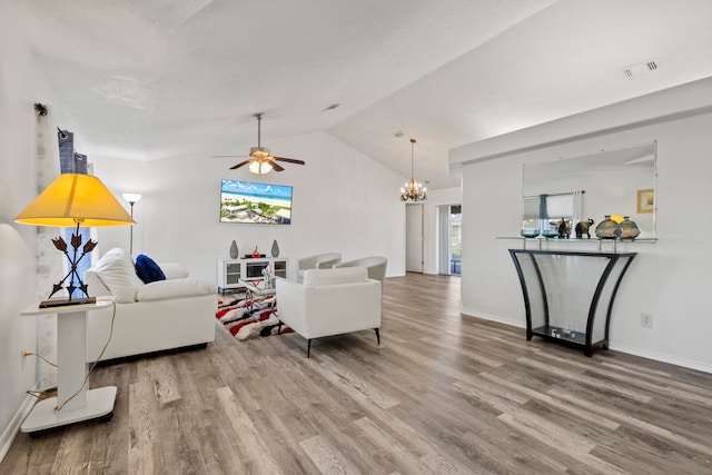 living room with ceiling fan with notable chandelier, wood-type flooring, and vaulted ceiling