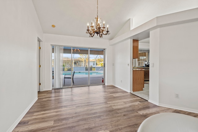 unfurnished dining area with wood-type flooring, lofted ceiling, and a notable chandelier