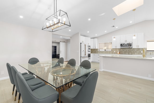 dining space with lofted ceiling with skylight and sink