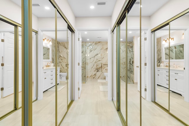 hallway featuring light tile patterned floors, a chandelier, and tile walls