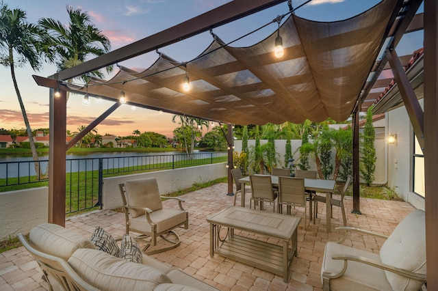 patio terrace at dusk with a pergola, an outdoor living space, and a water view