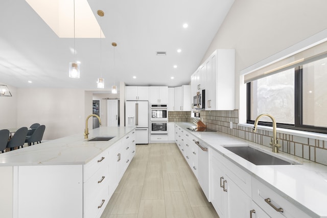 kitchen with a large island with sink, sink, white cabinets, and appliances with stainless steel finishes