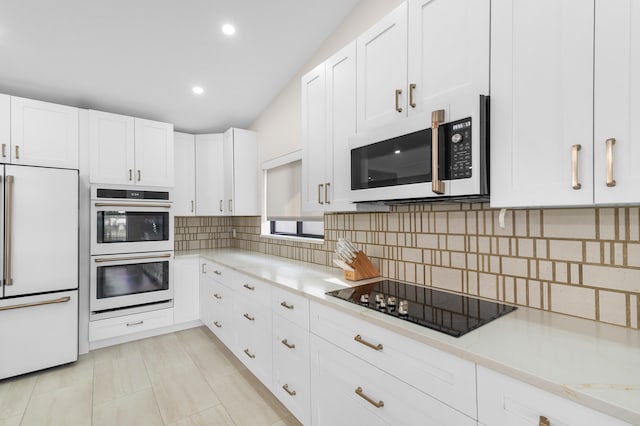 kitchen with decorative backsplash, light tile patterned floors, stainless steel appliances, and white cabinetry