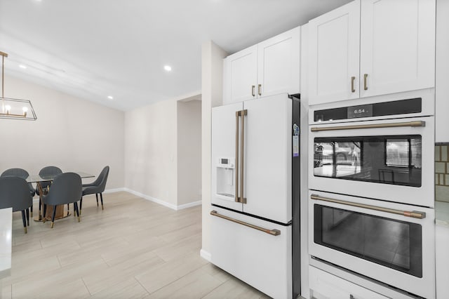 kitchen featuring stainless steel double oven, white refrigerator with ice dispenser, light hardwood / wood-style flooring, white cabinetry, and hanging light fixtures