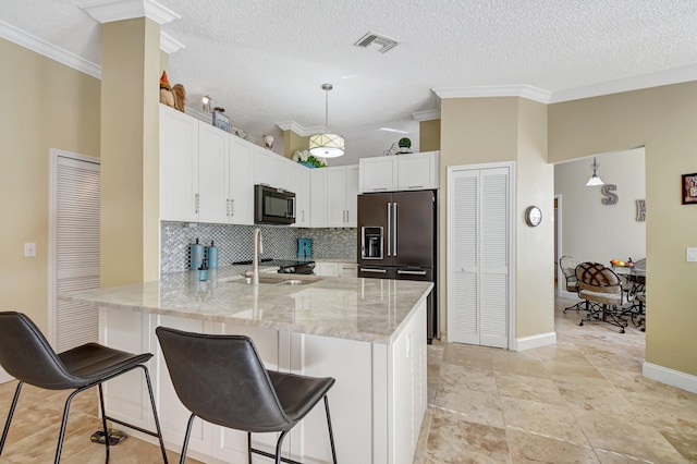 kitchen featuring kitchen peninsula, appliances with stainless steel finishes, sink, decorative light fixtures, and white cabinetry