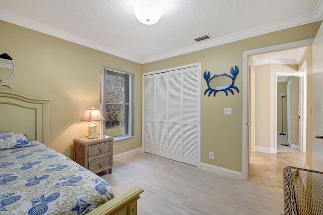 bedroom featuring light wood-type flooring, a textured ceiling, a closet, and crown molding