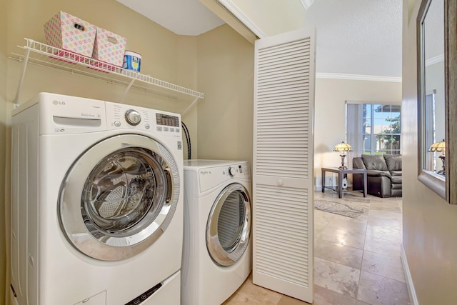 washroom with washing machine and clothes dryer and crown molding