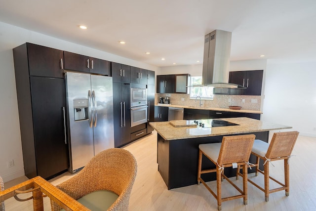 kitchen featuring a center island, stainless steel appliances, light stone counters, island range hood, and a breakfast bar