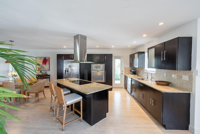 kitchen with island exhaust hood, a kitchen bar, stainless steel appliances, sink, and a kitchen island