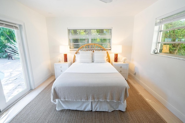 bedroom featuring access to exterior, light hardwood / wood-style floors, and multiple windows