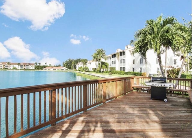 wooden deck with a water view and a grill