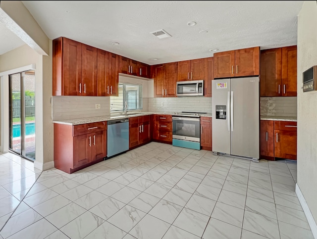 kitchen featuring tasteful backsplash, a textured ceiling, and appliances with stainless steel finishes