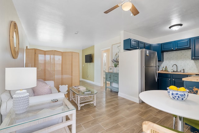 living room with ceiling fan, sink, and light wood-type flooring