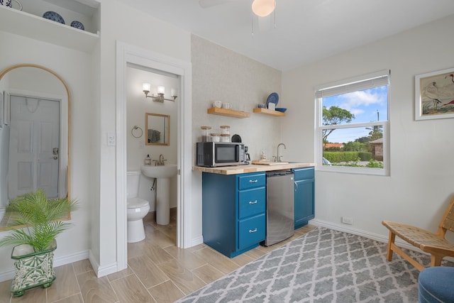 kitchen with stainless steel appliances, blue cabinets, ceiling fan, and sink