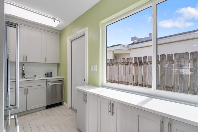 kitchen with tasteful backsplash, dishwasher, and sink